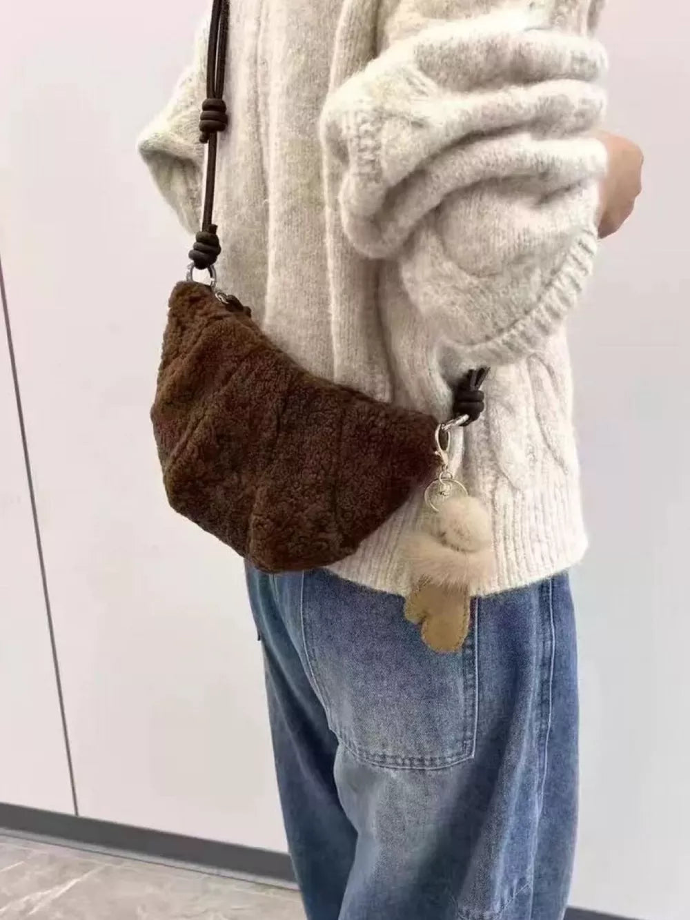 Plush knot strap furry crossbody bag in brown with a fuzzy charm.