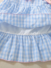 Blue gingham baby dress with ruffles and pink trim, featuring a bow detail.