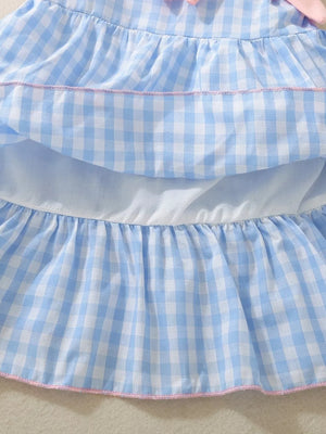 Blue gingham baby dress with ruffles and pink trim, featuring a bow detail.
