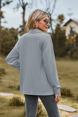 Textured knit polo shirt in light blue with long sleeves and a collared neckline.