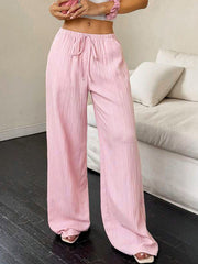 Pink crinkled wide leg pants with drawstring waist and a relaxed fit.