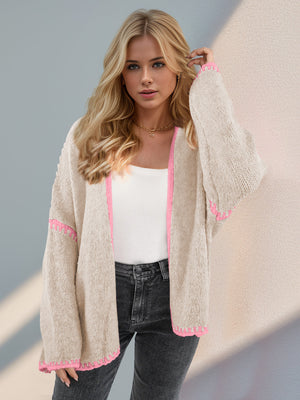 Oversized knit cardigan in tan with pink contrast stitching on edges and sleeves.