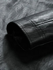 Black moto jacket detail showing textured faux leather and stitching.