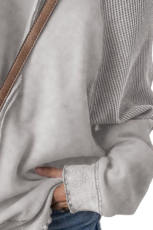 Gray waffle knit raglan sweatshirt with contrast striped sleeves and raw hem cuffs.