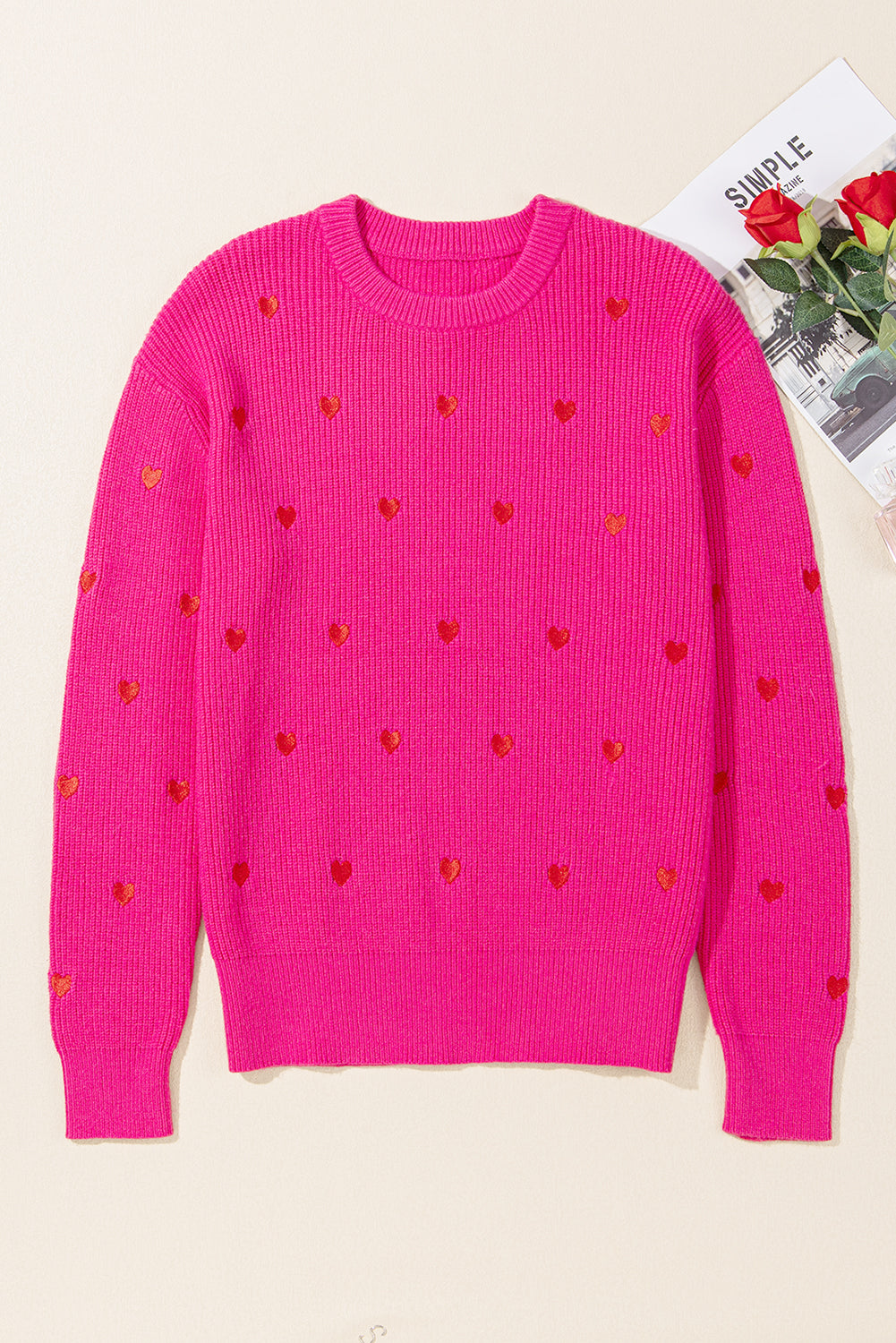 Pink ribbed crewneck sweater with all-over embroidered red hearts.
