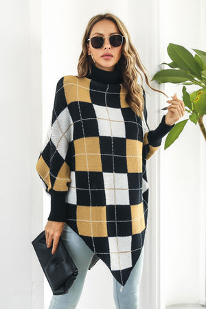 Geometric knit turtleneck cape sweater in plaid with black, white, and gold argyle pattern.