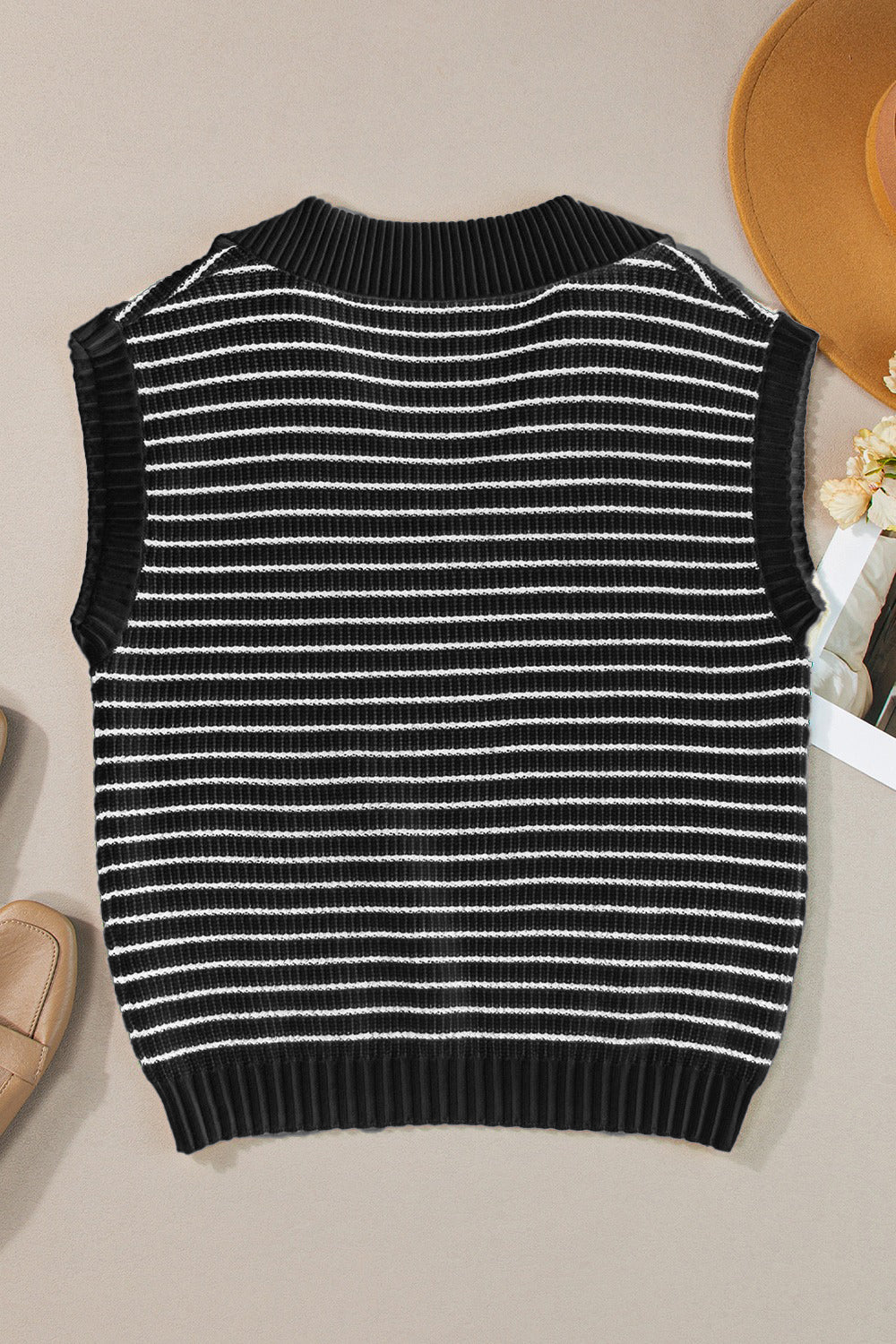 Black and ivory striped knit polo vest with a ribbed collar and hem.