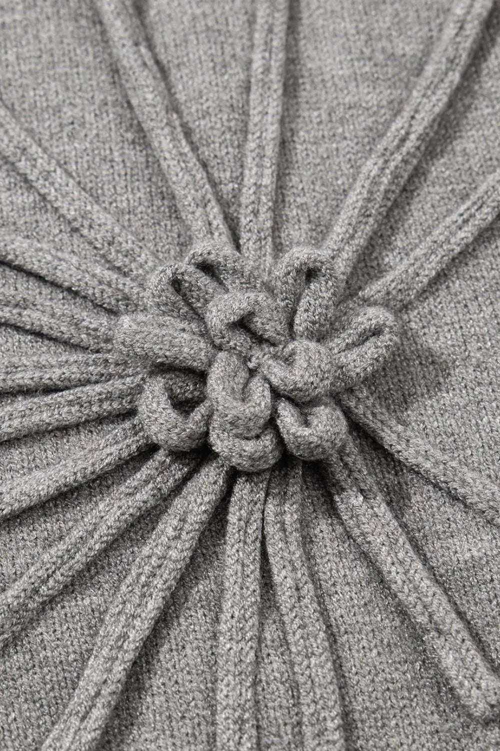 Gray knit blouse with a central embroidered bloom detail and ribbed texture.