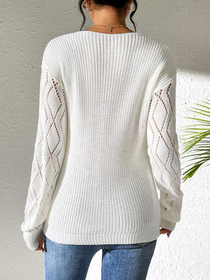 White openwork knit sweater with diamond lace sleeves and a ribbed hem.