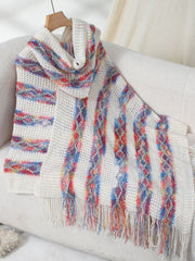 Textured knit hooded cape with colorful stripe and diamond patterns, and fringe detail.