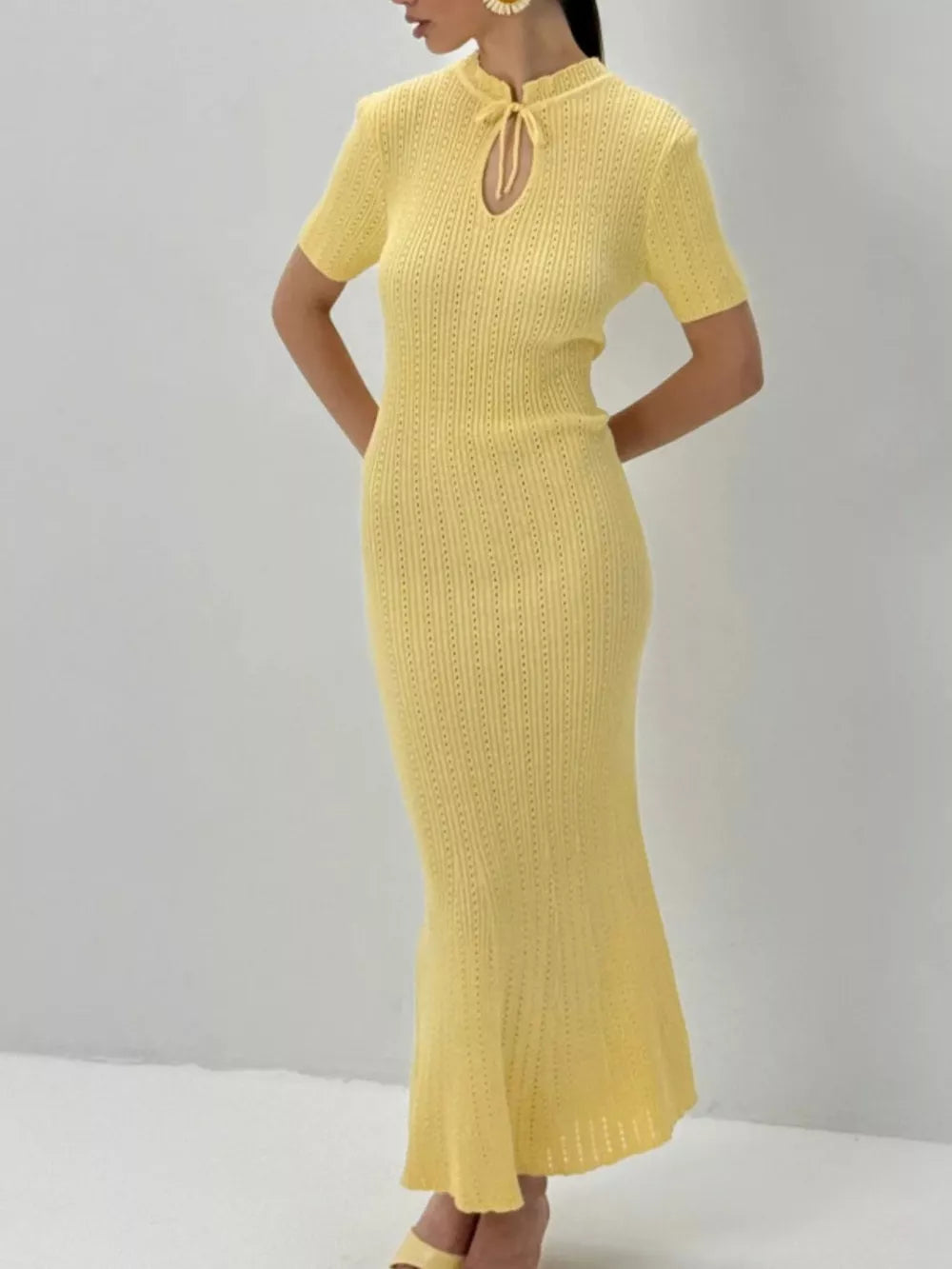 Pastel yellow knit mermaid dress with short sleeves and tied neckline detail.