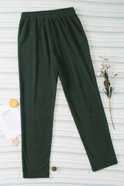 Dark green corduroy drawstring trousers with a relaxed fit and slant pockets.