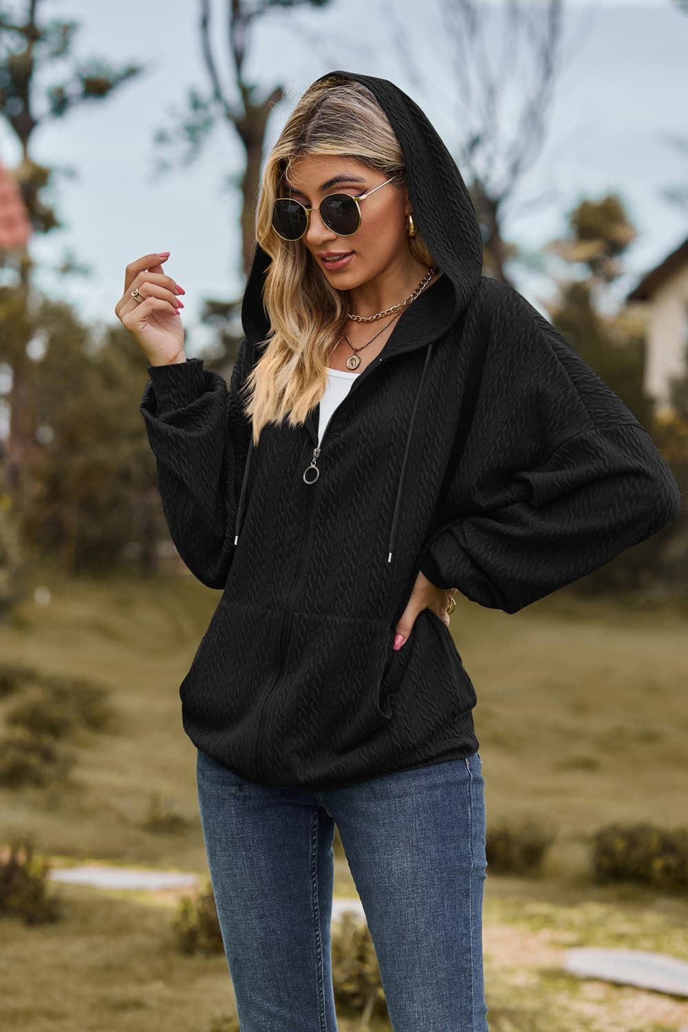 Black cable knit zip-up hoodie with textured fabric and a ring zipper pull.