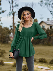 Green peplum blouse with gathered yoke and smocked cuffs.