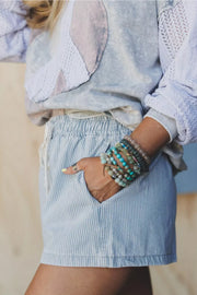 Light blue pinstripe denim shorts with drawstring waist and pockets.
