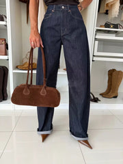 Dark blue denim wide-leg pants with cuffed hems and a brown suede shoulder bag.