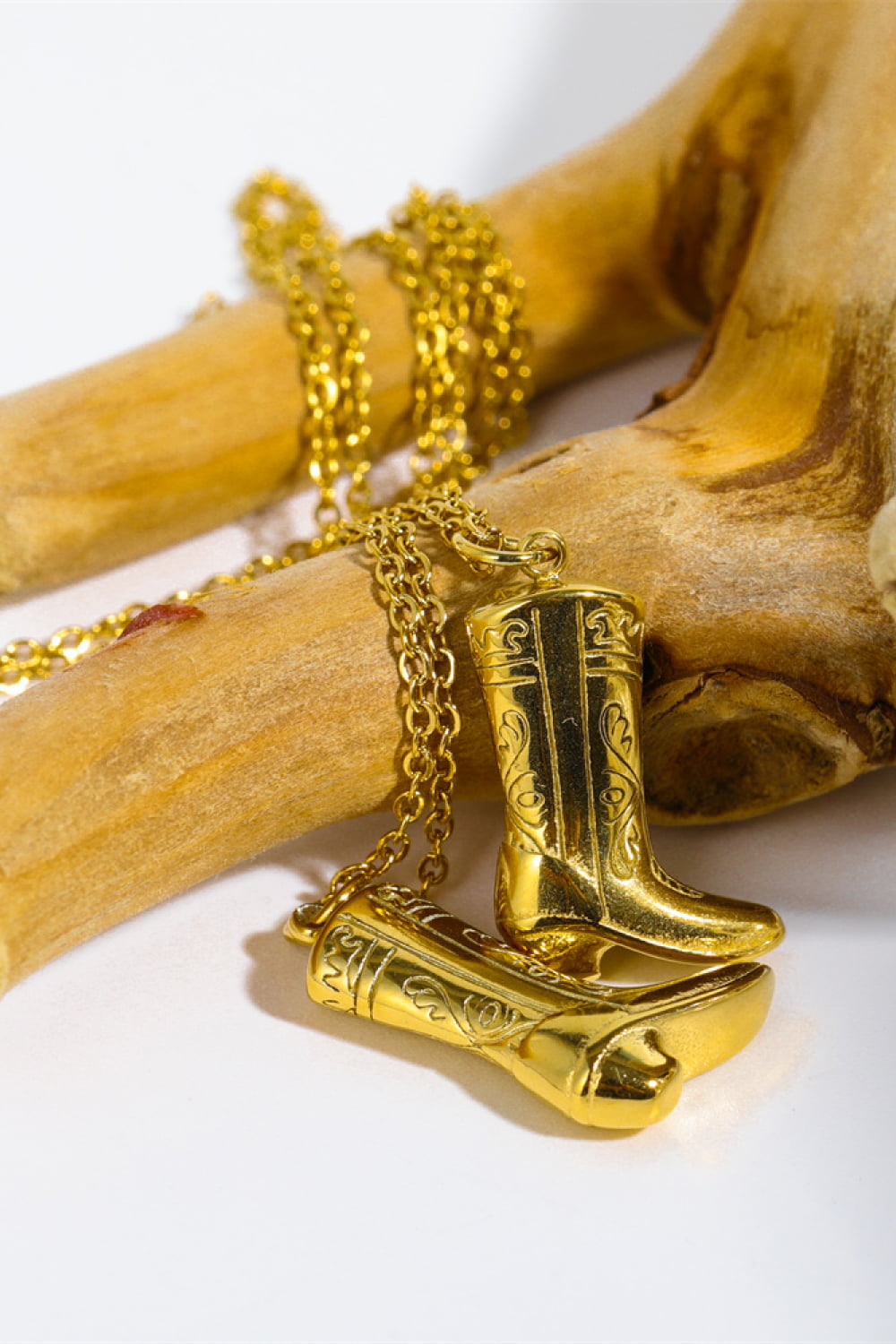 Gold cowboy boot charm necklace with ornate detailing on a gold chain.