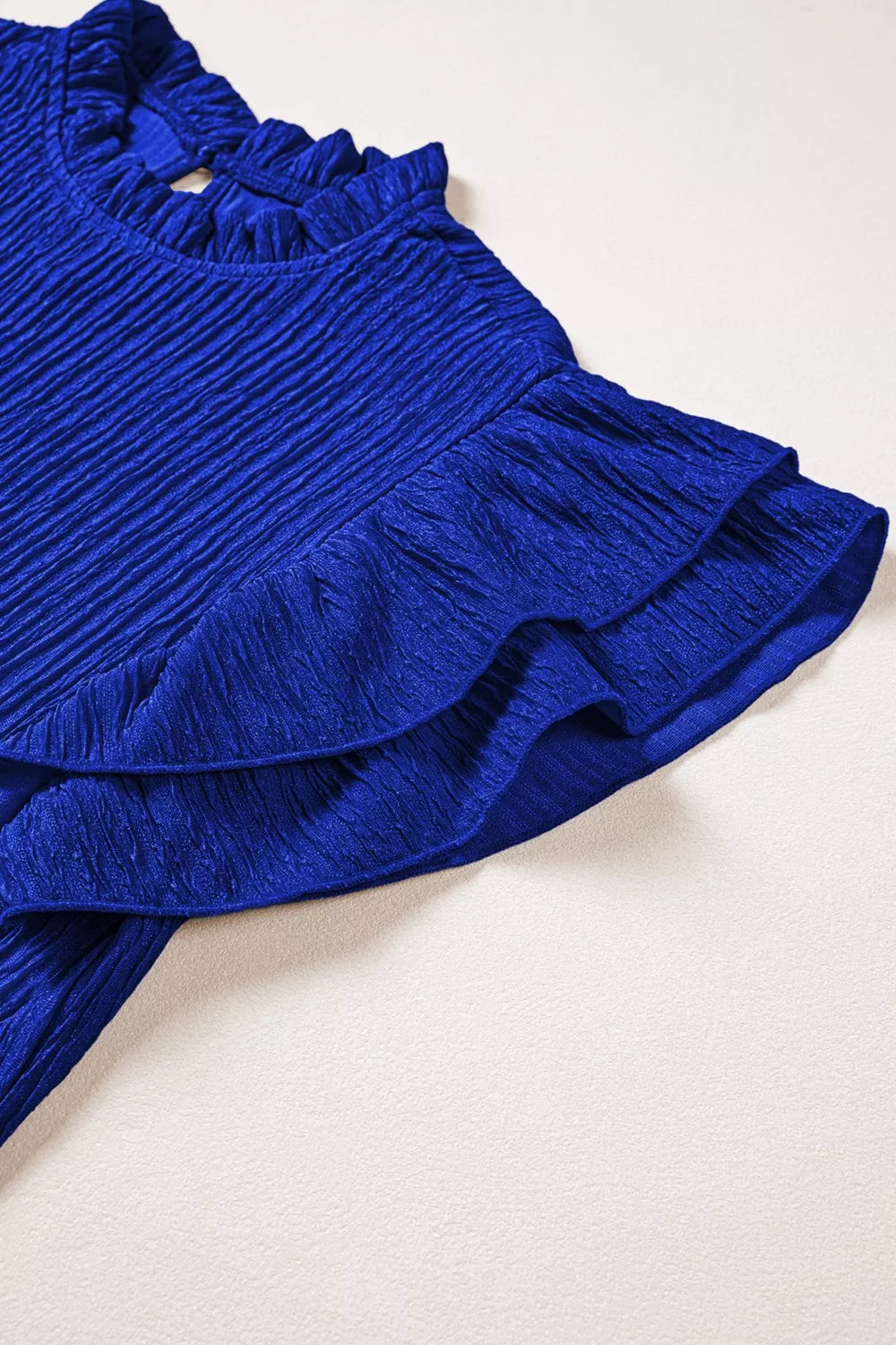Blue textured short sleeve shirt with ruffle trim on neckline and sleeves.