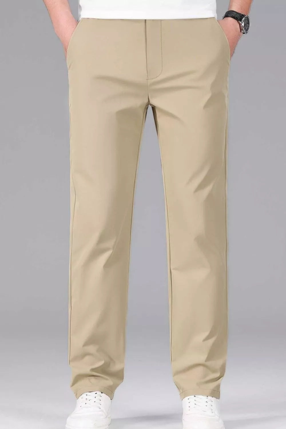 Men's khaki slim-fit stretch dress pants with a straight leg, styled casually with white sneakers.