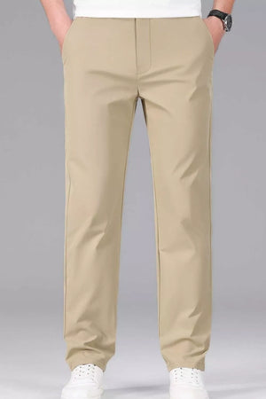 Men's khaki slim-fit stretch dress pants with a straight leg, styled casually with white sneakers.