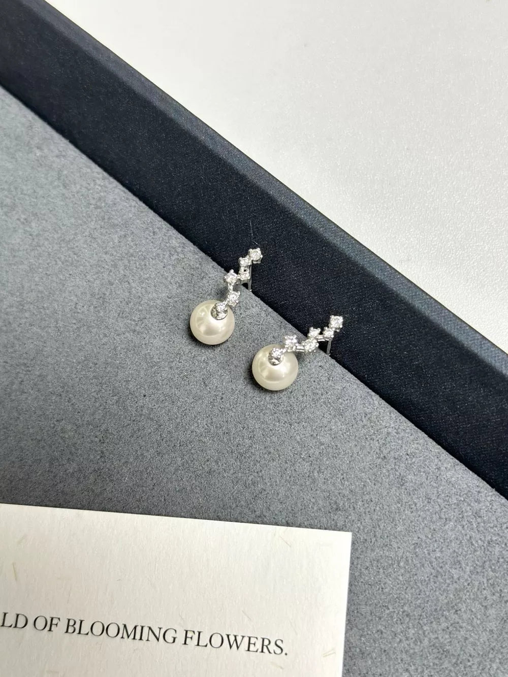 Elegant sterling silver drop earrings with ivory pearls and zircon accents.