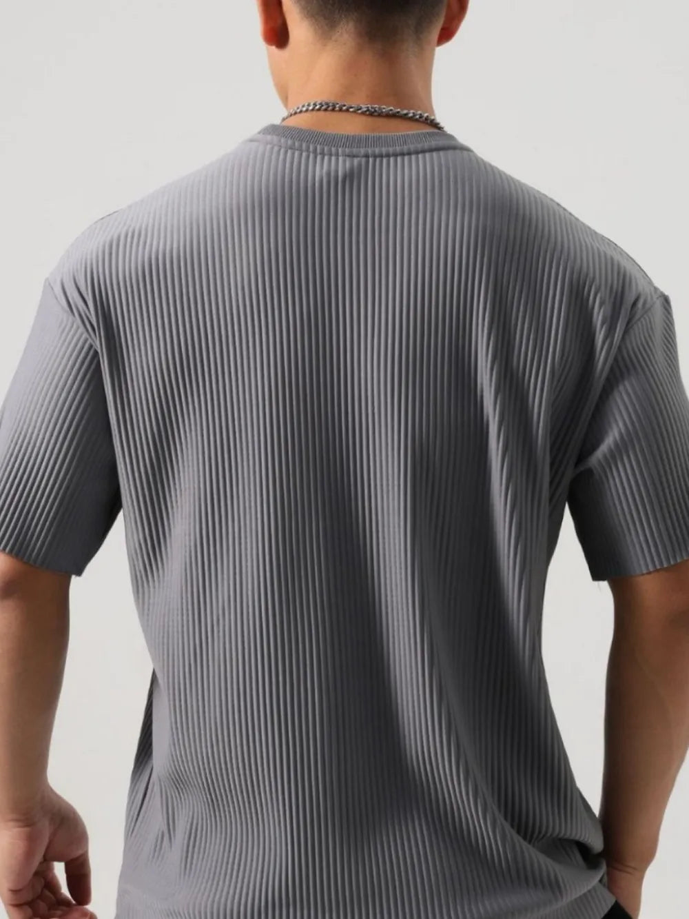 Dark gray t-shirt with sculpted vertical pleats and an oversized fit.