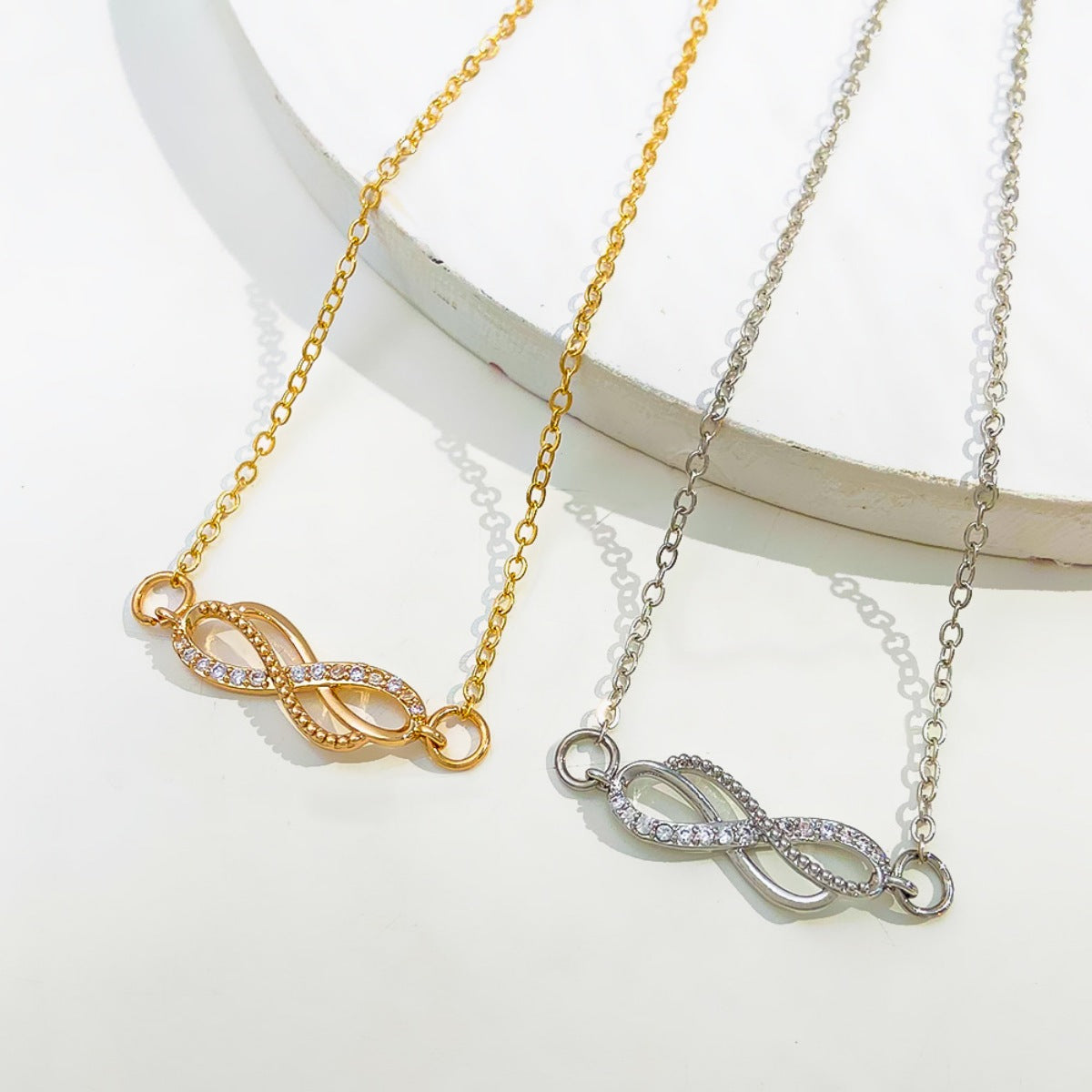 Gold and silver infinity knot charm bracelets with cubic zirconia details