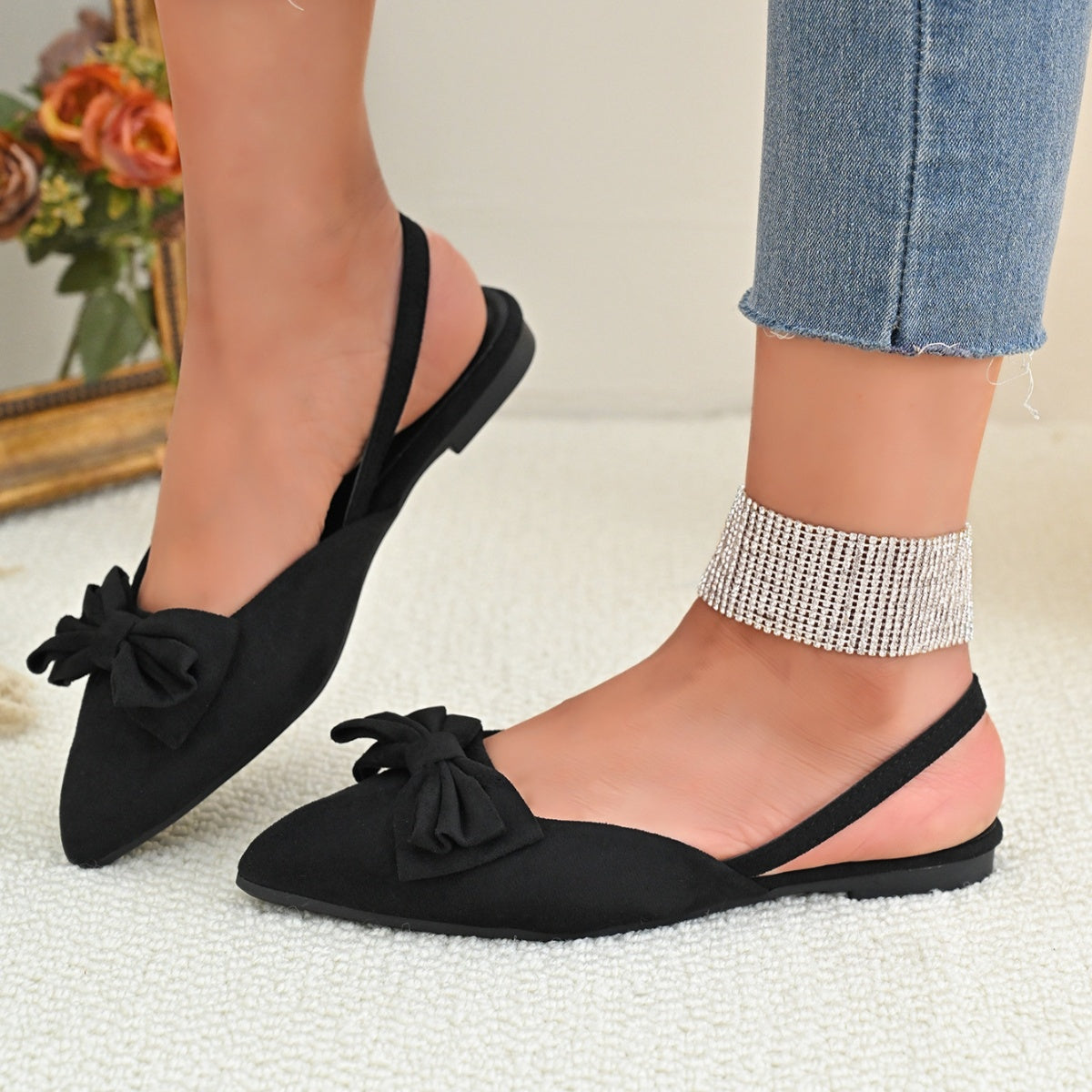 Black slingback flats with bow detail and pointed toe.