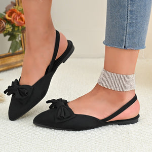 Black slingback flats with bow detail and pointed toe.