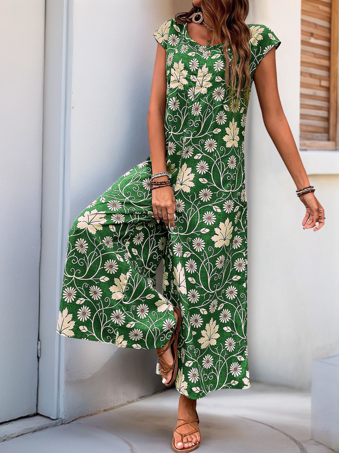 Dark green botanical print culotte jumpsuit with short sleeves and a round neckline.