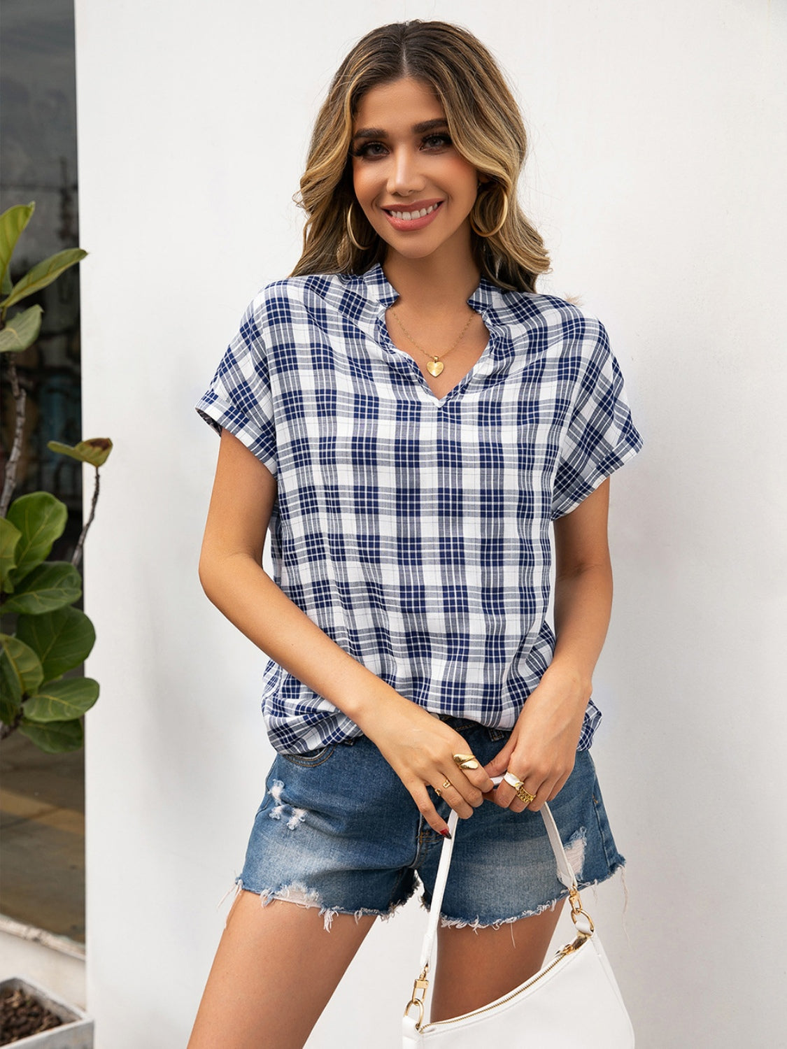 Notched plaid henley blouse in blue and white with short sleeves and a V-neck.