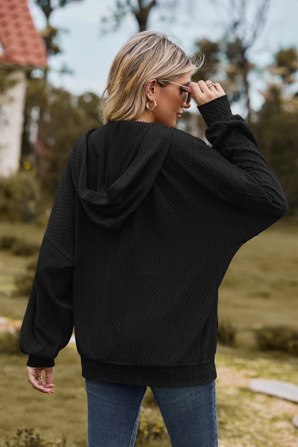Black cable knit zip-up hoodie with textured fabric and relaxed fit.
