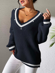 Dark navy knit sweater with V-neck, white stripes, and pearl buttons, styled casually.
