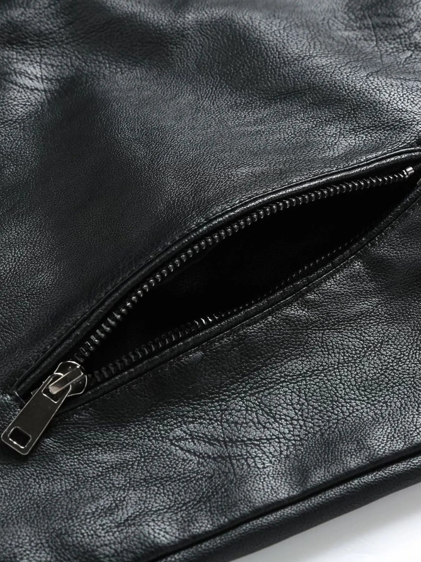 Black plus-size moto jacket detail showing a zippered pocket with silver hardware.