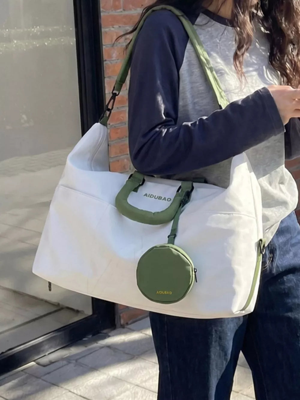White nylon duffle bag with green accents and detachable pouch