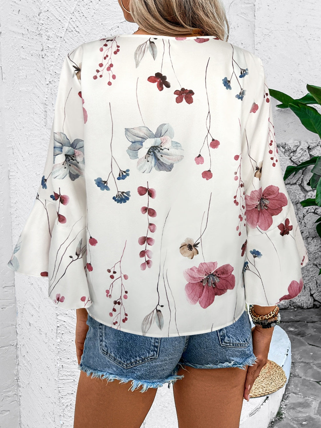 White floral print blouse with bell sleeves and lace trim detail.