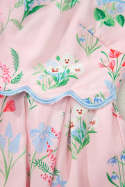 Pink midi dress with a multicolor wildflower print and blue scalloped trim detail.