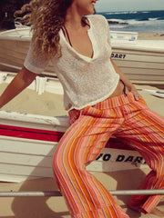 Chic knit sleeve blouse with deep V-neck, paired with striped wide-leg pants.