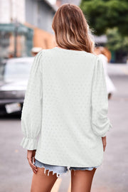 White textured dot v-neck blouse with ruffle cuffs and long sleeves.