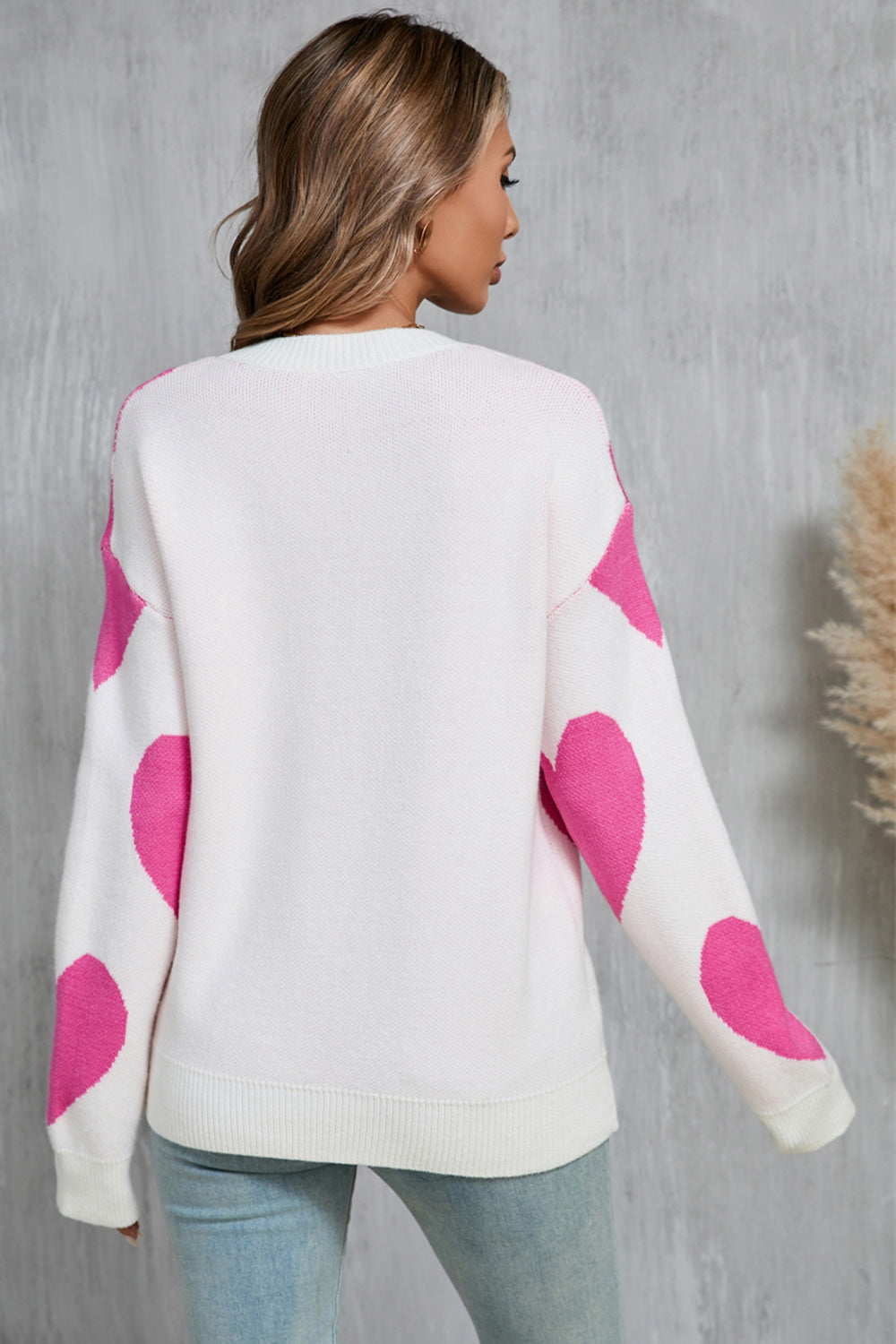 White knit sweater with fuchsia pink heart patches on sleeves and back.