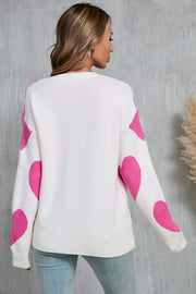 White knit sweater with fuchsia pink heart patches on sleeves and back.