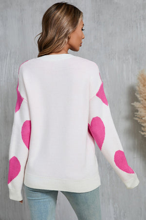 White knit sweater with fuchsia pink heart patches on sleeves and back.