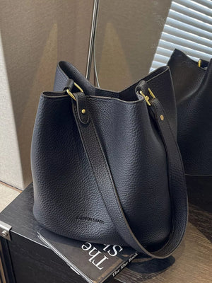 Black pebbled leather tote bag with gold hardware and adjustable strap.