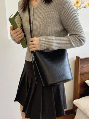Black distressed vintage bucket crossbody bag with adjustable strap.