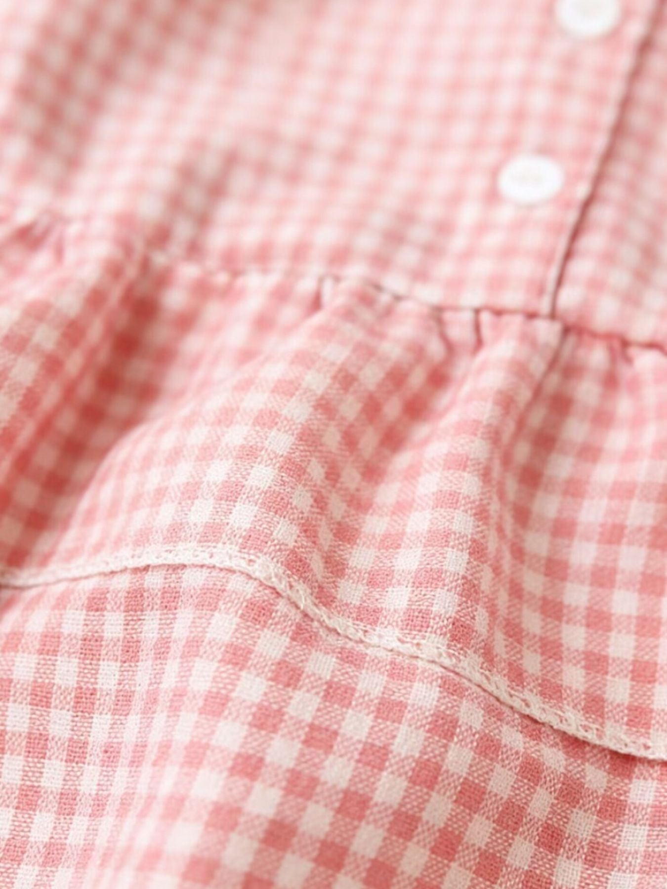 Blush pink gingham baby dress with ruffles and buttons.