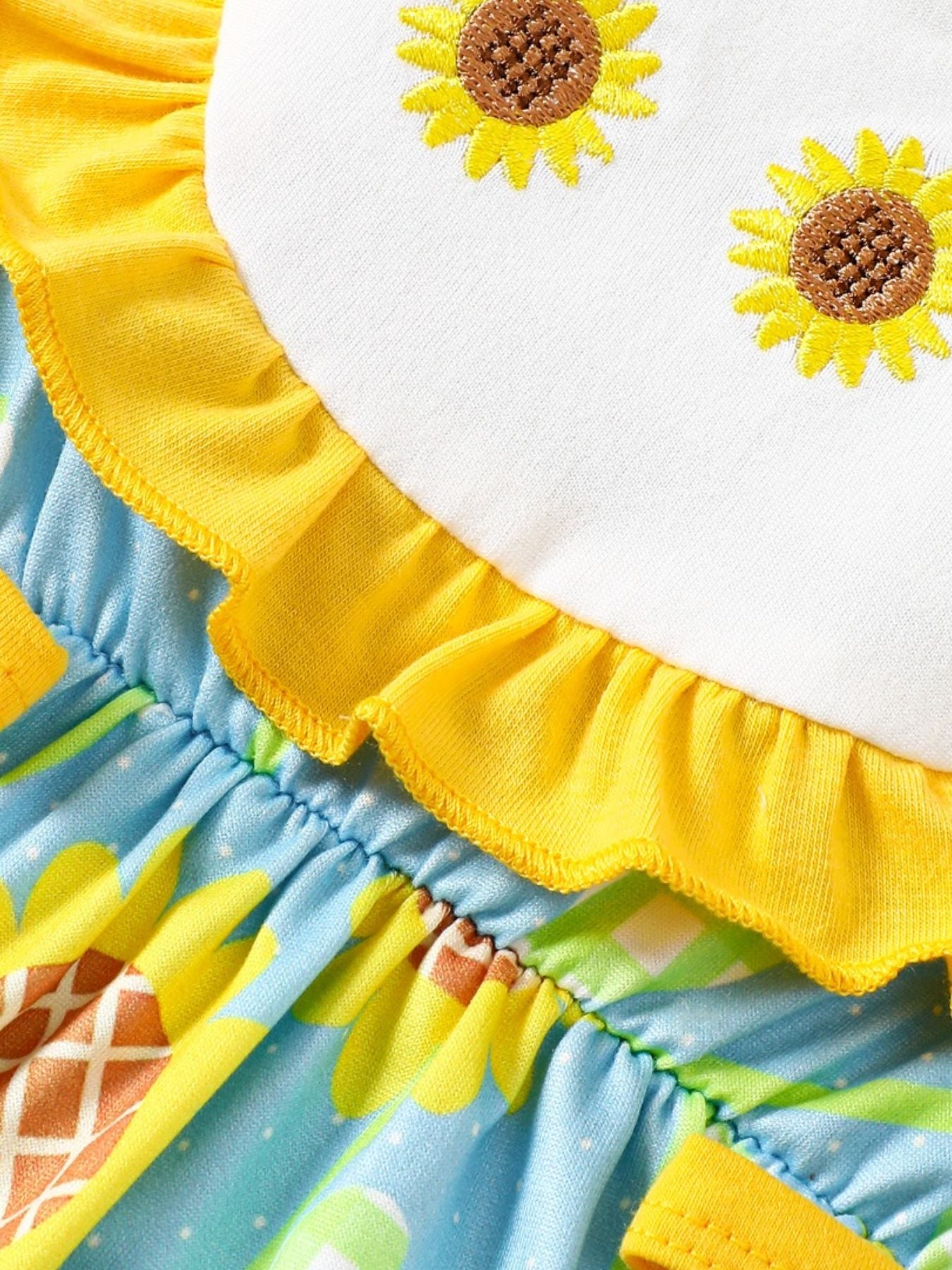 Baby yellow ruffled one-piece with embroidered sunflowers and blue floral print.
