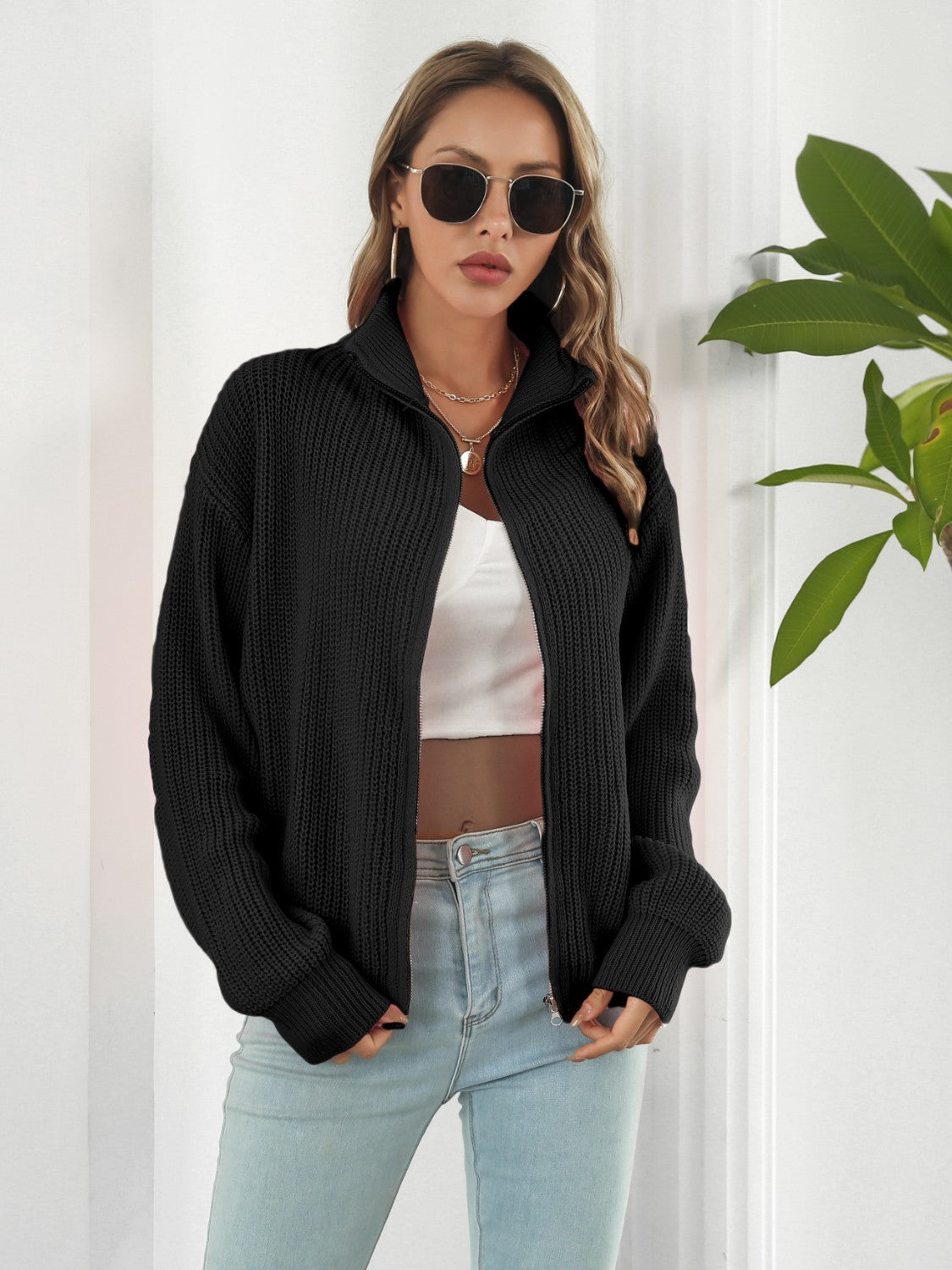 Black ribbed knit zip-up sweater with a mock neck and long sleeves.