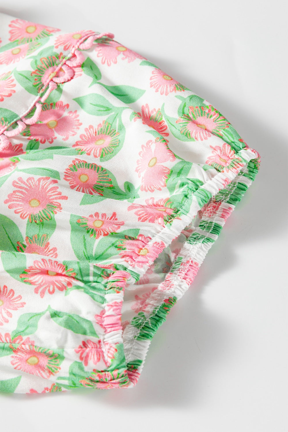 Women's tiered mini dress with pink floral print, ruffled neckline and elasticized hem.