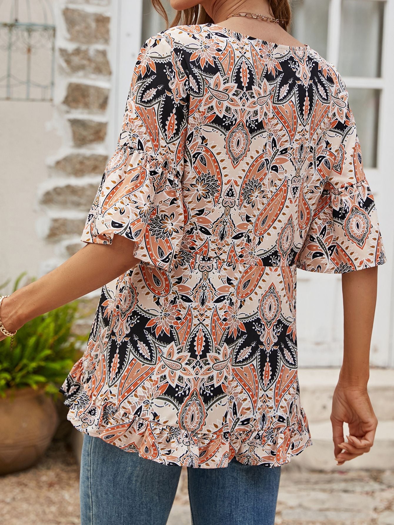 Paisley print blouse with ruffle hem and flutter sleeves in tangerine and burgundy colors.