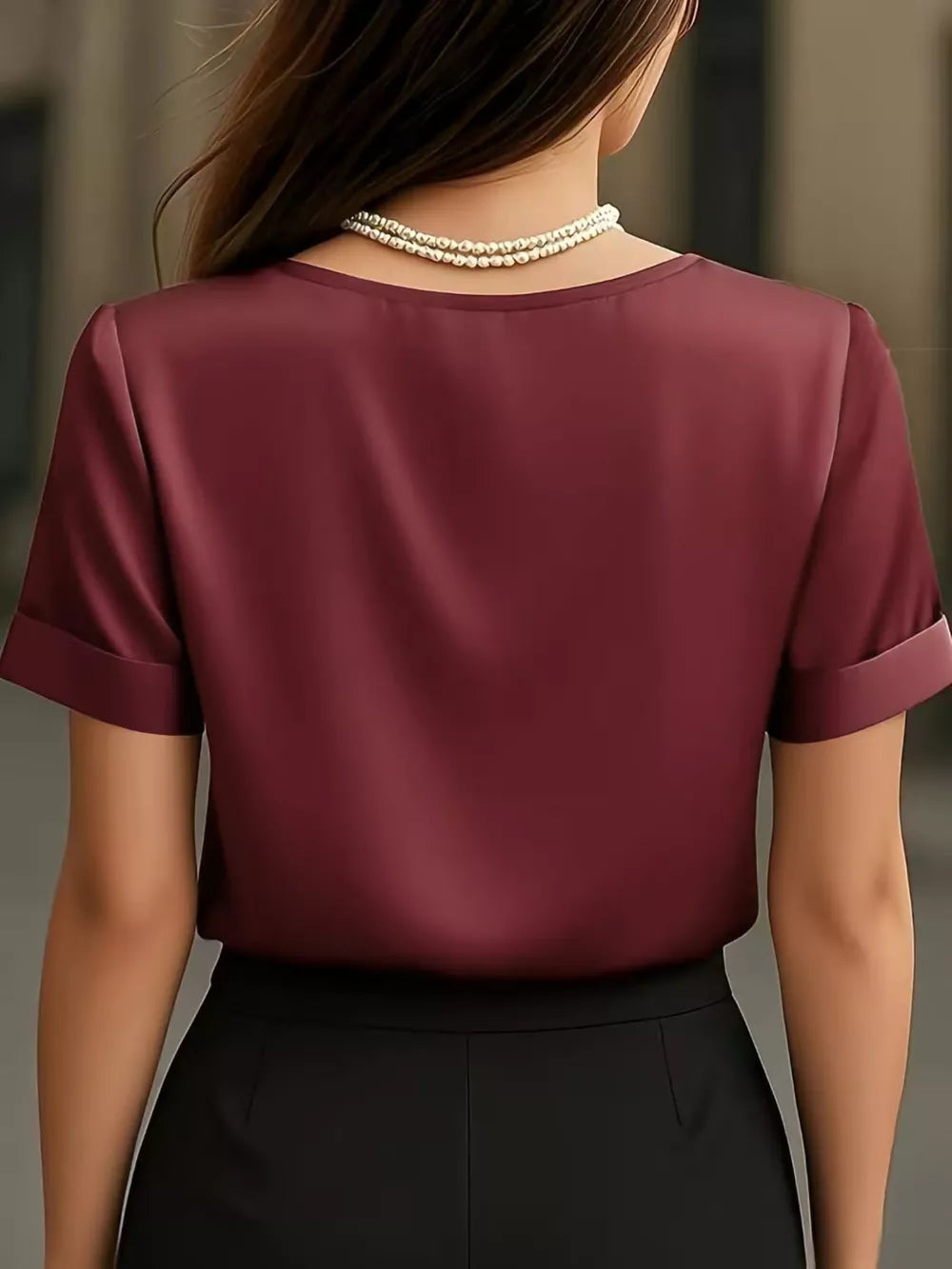 Wine red satin shirt with cuffed sleeves and V-neck, styled with a pearl necklace.